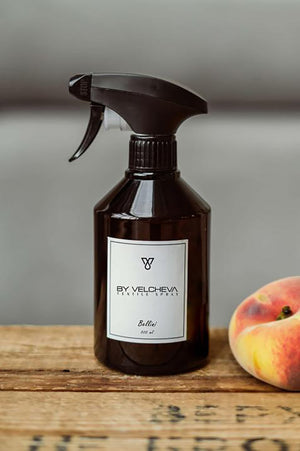 Braune SprĂĽhflasche mit weissem Etikett neben Pfirsich