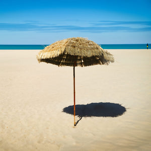 Beiger Sonnenschirm mit Holz Ständer im Hawaii Stil in einem Anwendungsbeispiel am Strand
