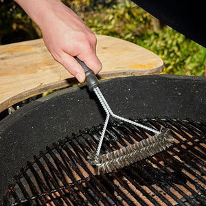 Silberne Grillbürste mit schwarzem Griff in einem Anwendungsbeispiel auf einem Grill