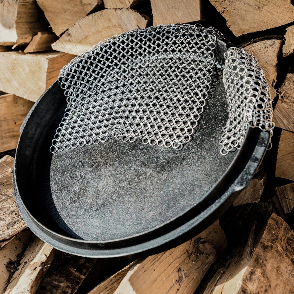 Silberner Ringreiniger in einem Feuertopf mit Holzstapel im Hintergrund